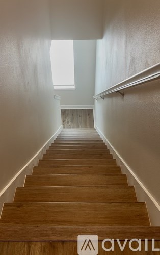 A long flight of wooden stairs leads to a bright window.