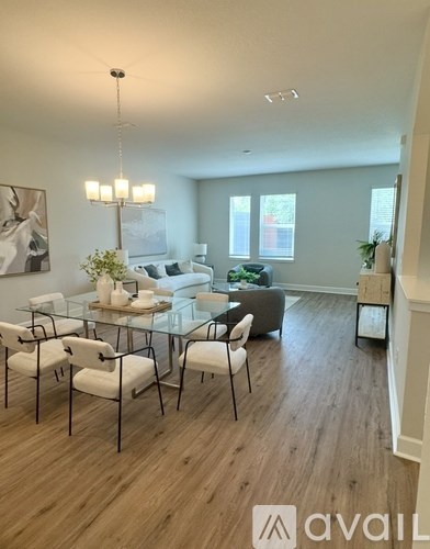 A modern living room with a glass table and white chairs.