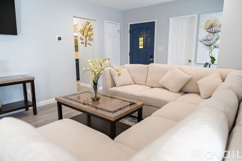 A living room with a white couch and a glass coffee table.