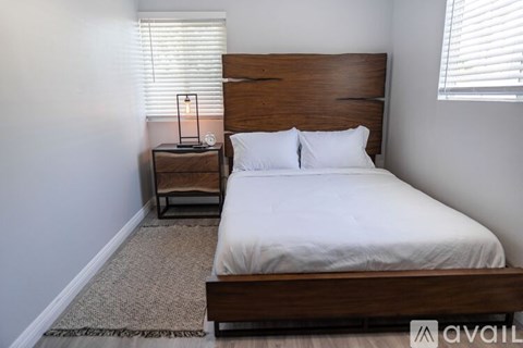 A bedroom with a large bed and a small table with a lamp on it.