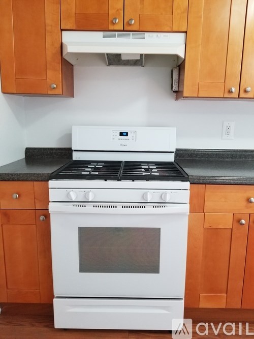 A white stove top oven with a glass door is in a kitchen with wooden cabinets.