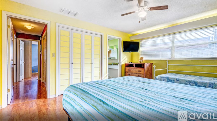 A bedroom with a bed, dresser, and sliding glass doors.