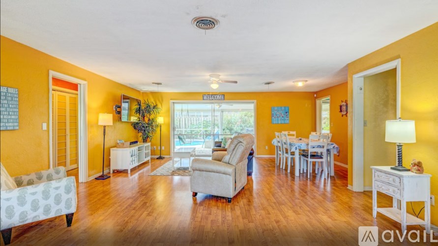 A living room with a white sofa and a dining table with chairs.
