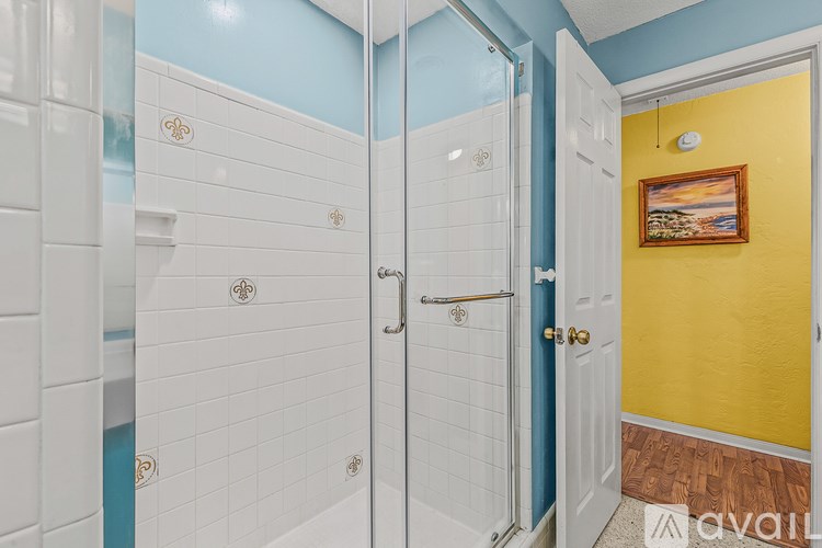 A bathroom with a white tiled shower and a yellow door.