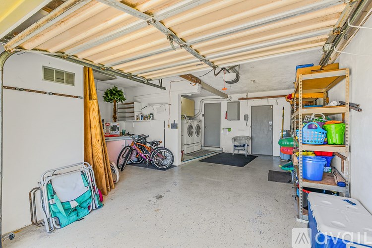 A storage room with a washer and dryer, a bicycle, and various items on shelves.