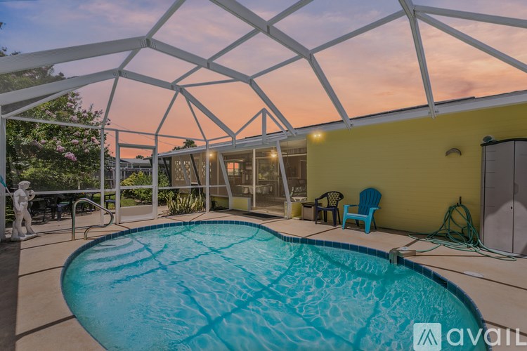 A pool under a white roof with a yellow wall and a blue chair.