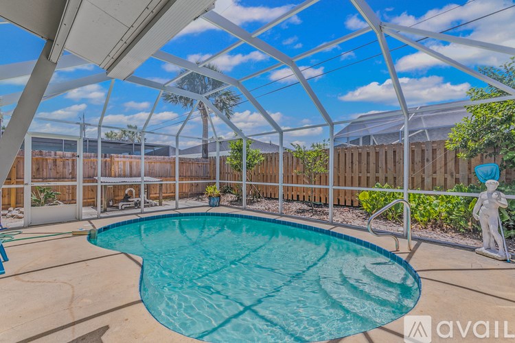 A pool under a white canopy with a wooden fence in the background.