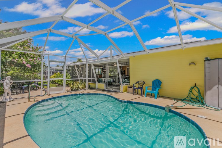A pool under a white roof with a yellow wall and a statue.
