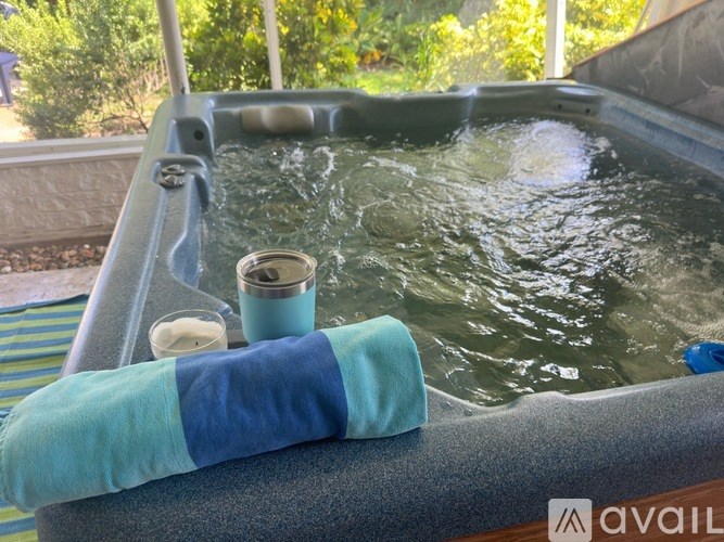 A hot tub with a blue towel and a cup on the side.