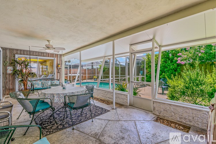 A patio with a table and chairs overlooking a pool.