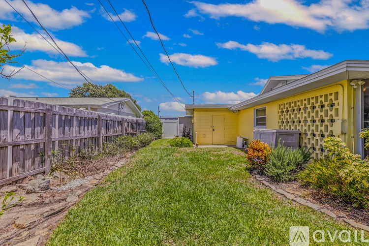 A yellow house with a fence and green grass in front.