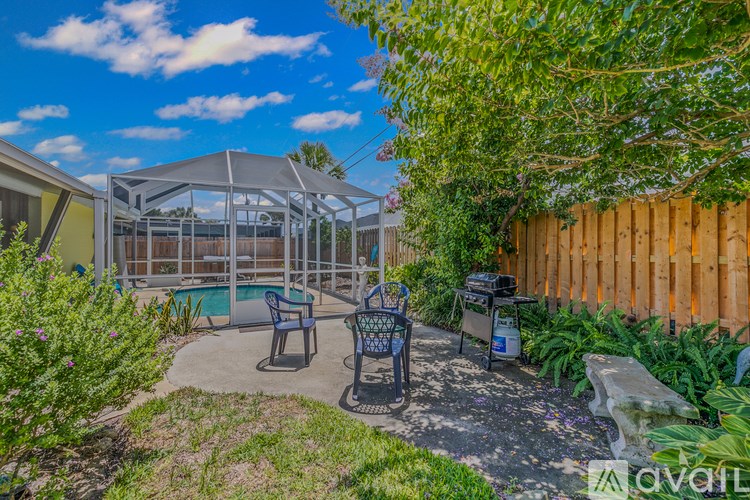 A backyard with a patio, a pool, and a wooden fence.