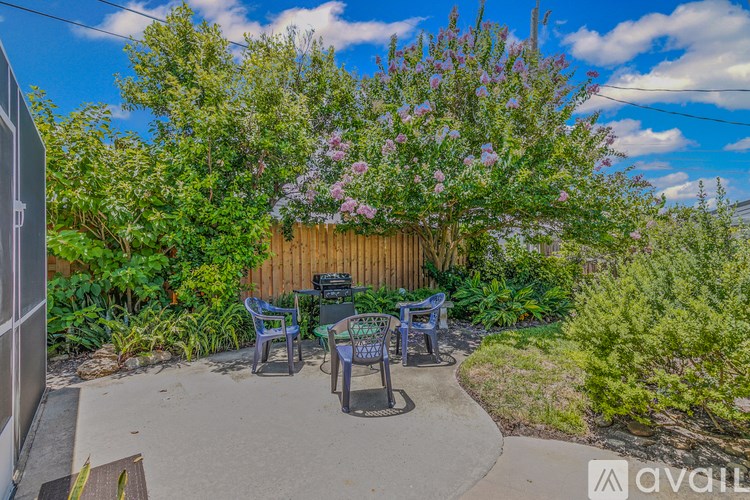 A backyard with a wooden fence and a table surrounded by chairs.