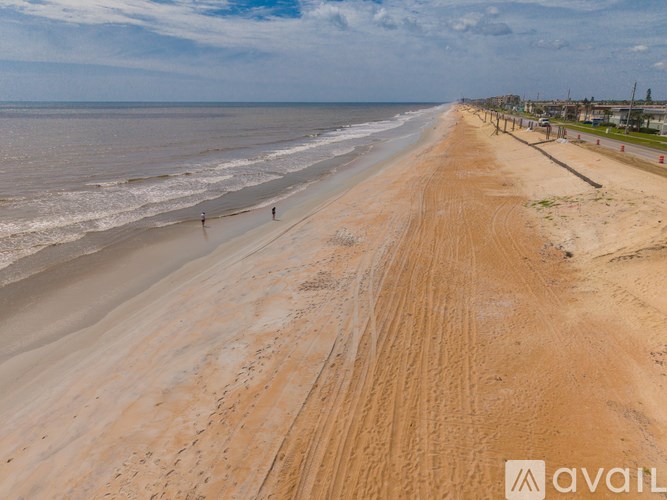 A beach with people walking on the sand and the ocean in the background.
