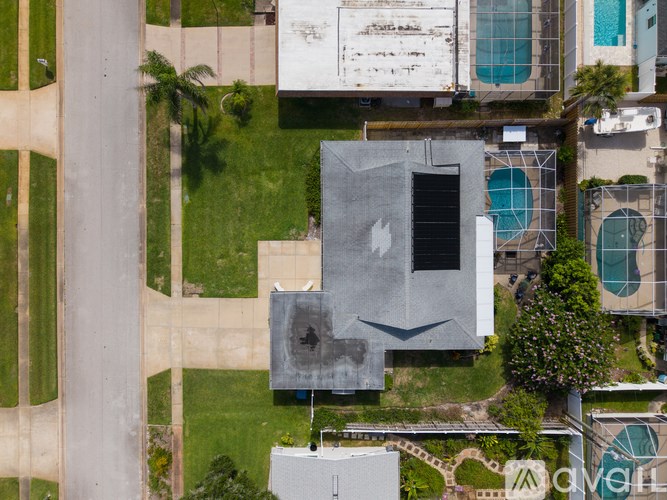 A modern building with a grey exterior is surrounded by a green lawn.