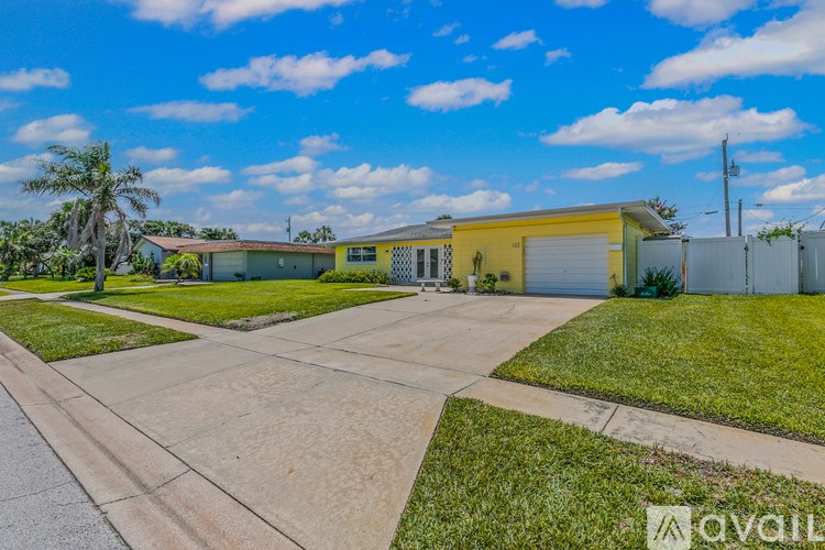 A living room with a white couch and a yellow wall.