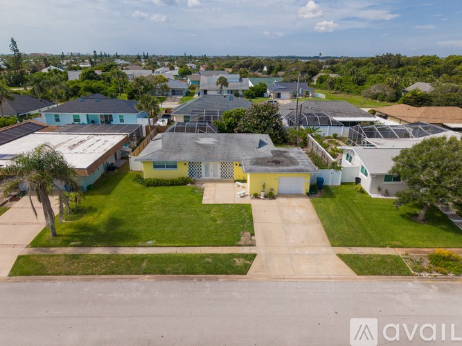 A bird's eye view of a residential area with houses and a yellow building in the foreground.