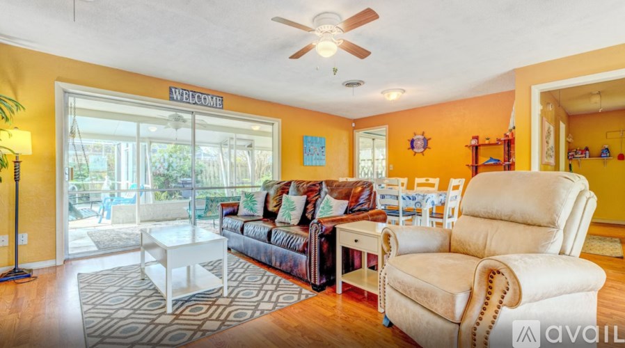 A living room with a sofa, chairs, and a welcome sign on the door.