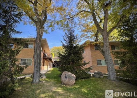 A large rock sits in the grass in front of a building.