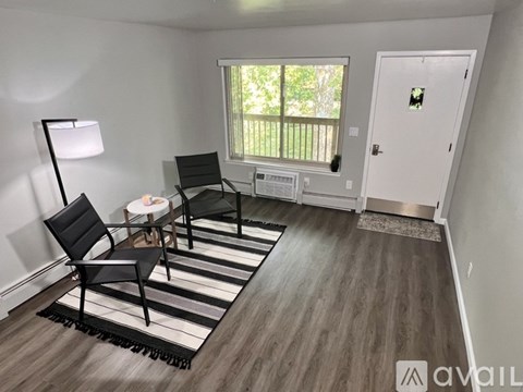 A room with a black chair and a black and white striped rug.