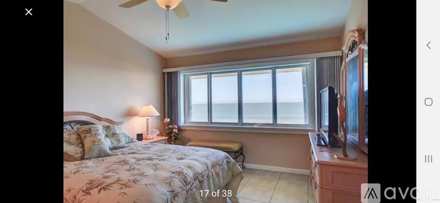 A bedroom with a large bed and a window overlooking the ocean.
