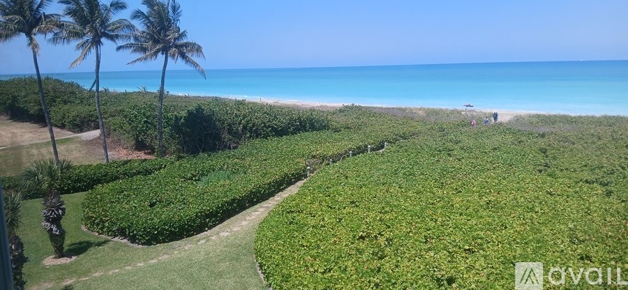 A beachfront property with a lush green lawn and a view of the ocean.
