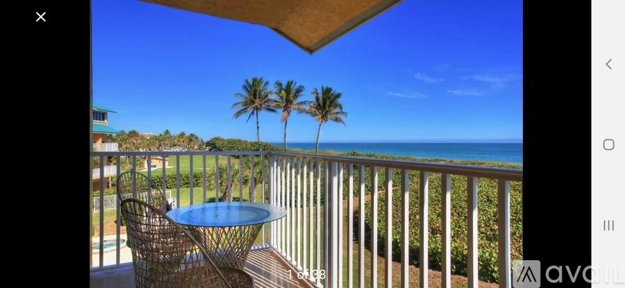 A balcony with a table and chairs overlooking the ocean.