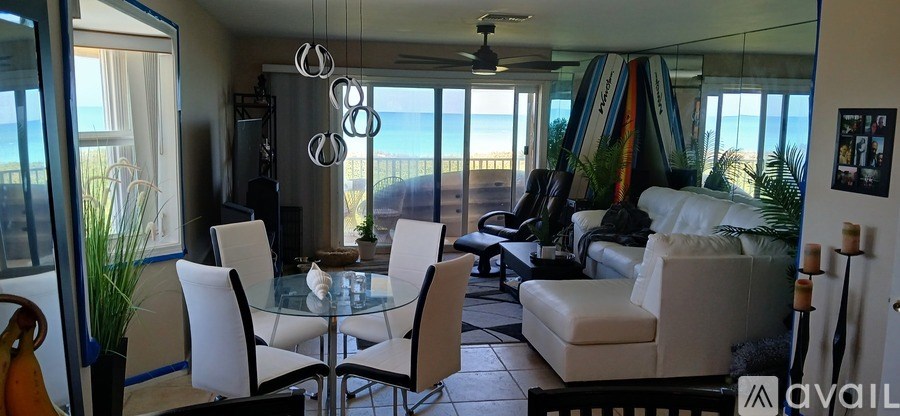 A glass dining table surrounded by white chairs in a room.