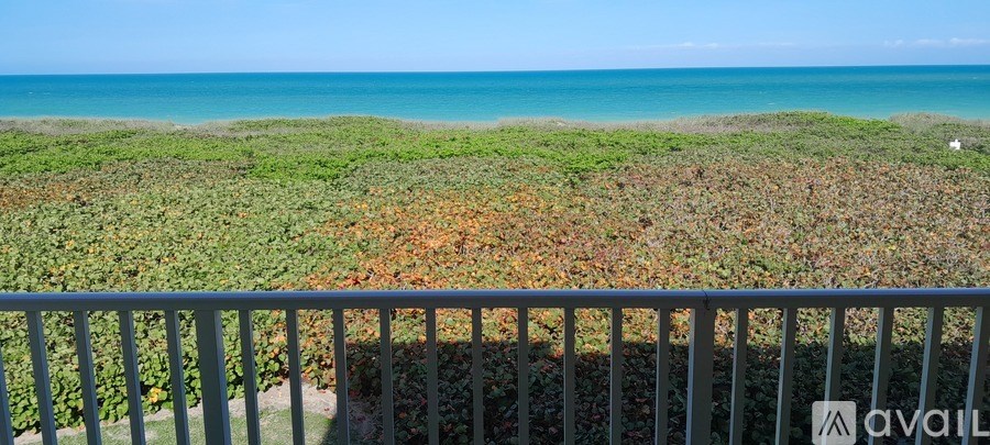 A balcony overlooks a beach with a metal railing.