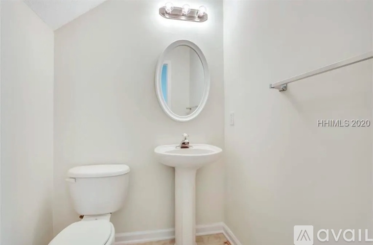A white toilet sits next to a pedestal sink in a small bathroom.