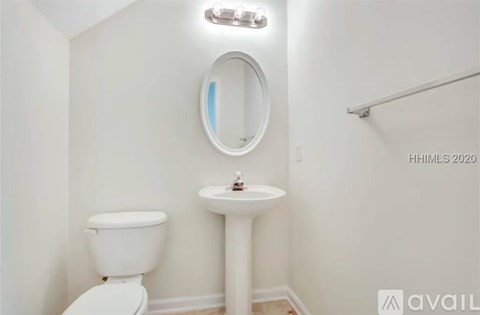 A white toilet sits next to a pedestal sink in a small bathroom.