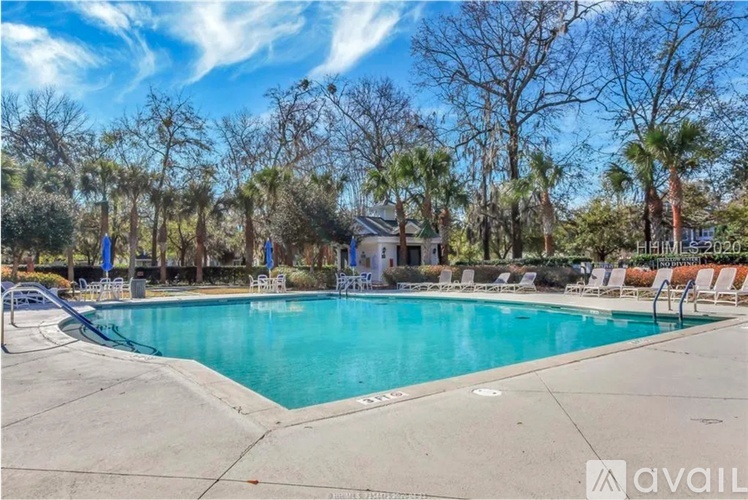 A swimming pool surrounded by trees and lounge chairs.