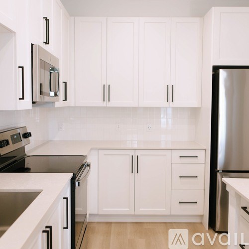 A kitchen with white cabinets and a black refrigerator.