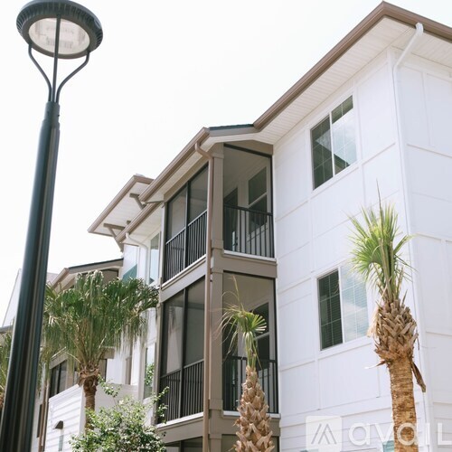 A white building with balconies and palm trees in front.