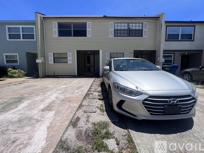 A silver car is parked in front of a two-story apartment building.