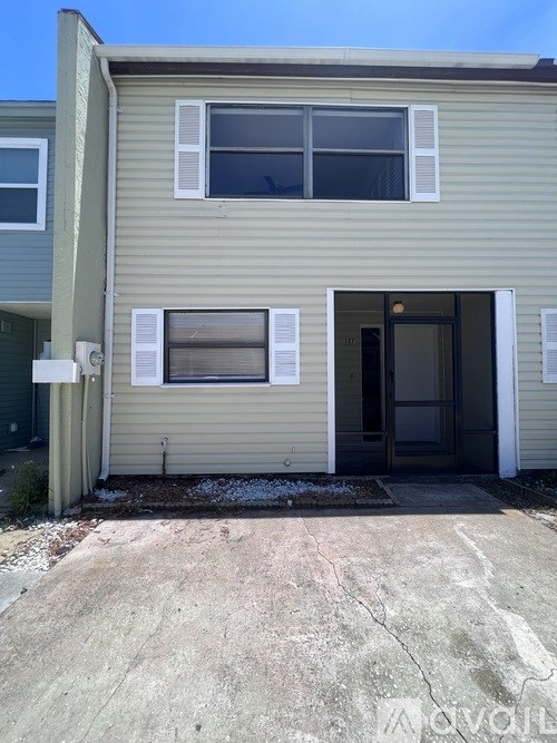 A beige house with a brown door and a window with blinds.