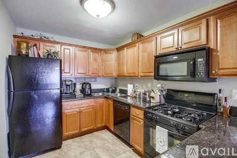 A kitchen with wooden cabinets and black appliances.