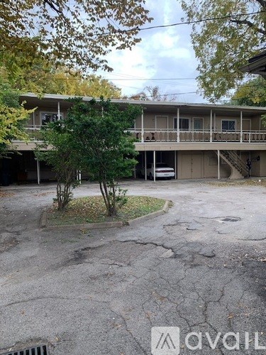 A tree in front of a building with a sign that says "avail".