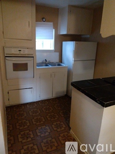 A kitchen with white appliances and brown patterned flooring.