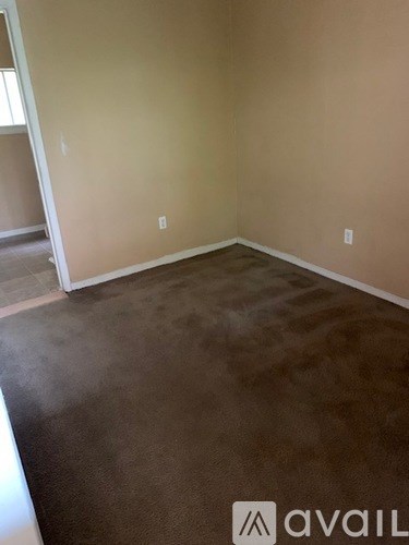 A room with brown carpet and beige walls.
