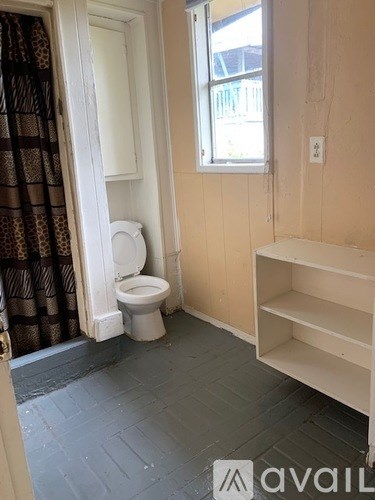 A bathroom with a toilet and a shelf.