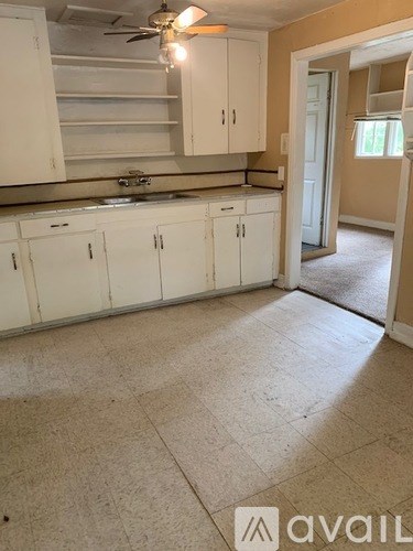 A kitchen with white cabinets and a fan on the ceiling.
