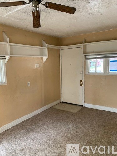 A room with a ceiling fan and a door.