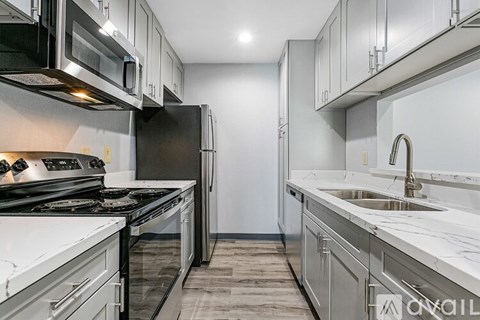 A modern kitchen with stainless steel appliances and a marble countertop.
