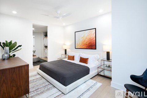 A bedroom with a bed, a chair, and a painting on the wall.