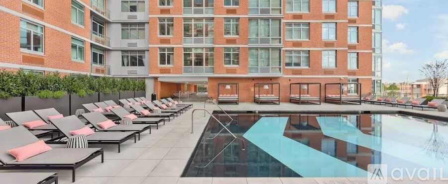 A large pool surrounded by lounge chairs in front of a red brick building.