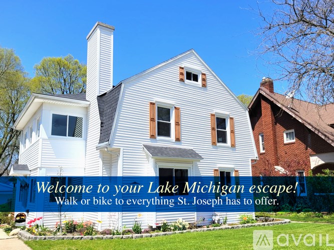 A white house with a blue banner that says "Welcome to your Lake Michigan escape! Walk or bike to everything St. Joseph has to offer."
