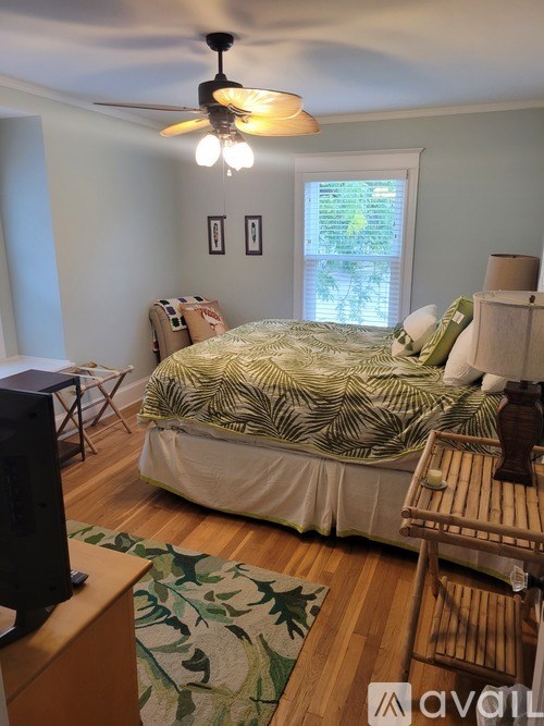 A bedroom with a bed, a chair, and a ceiling fan.