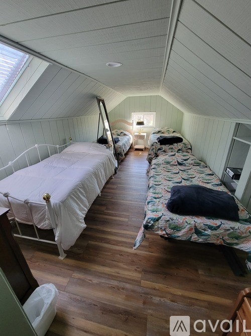 A room with two beds and wooden floors.