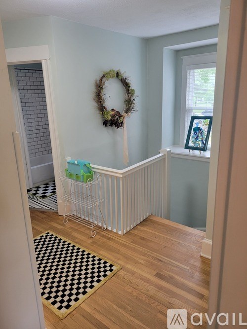 A room with a wreath on the wall and a black and white checkered rug on the floor.
